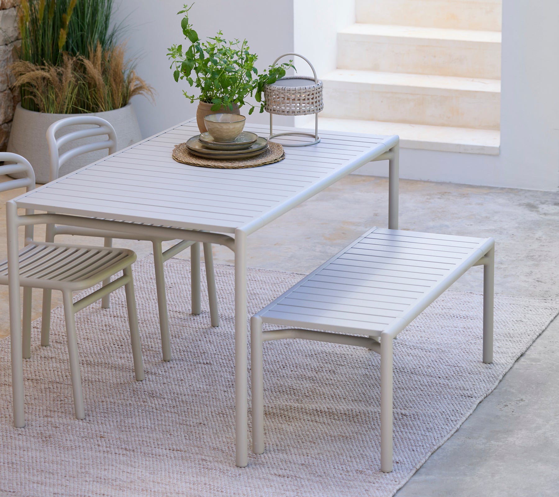 Modern witte eetkamertafel met bijpassende bank en stoel in een minimalistische omgeving.