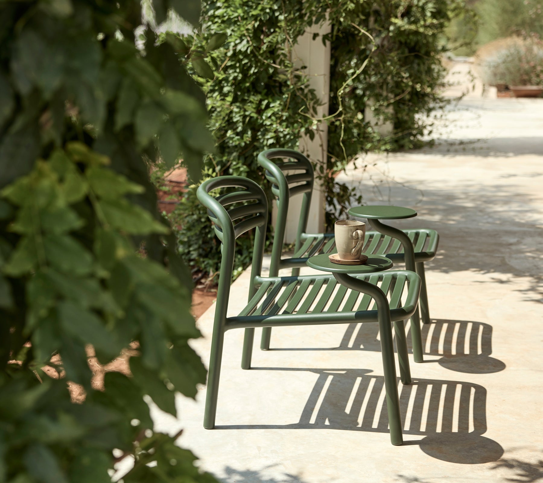 Groene stoelen en een bijzettafel in een buitenomgeving met weelderig groen.