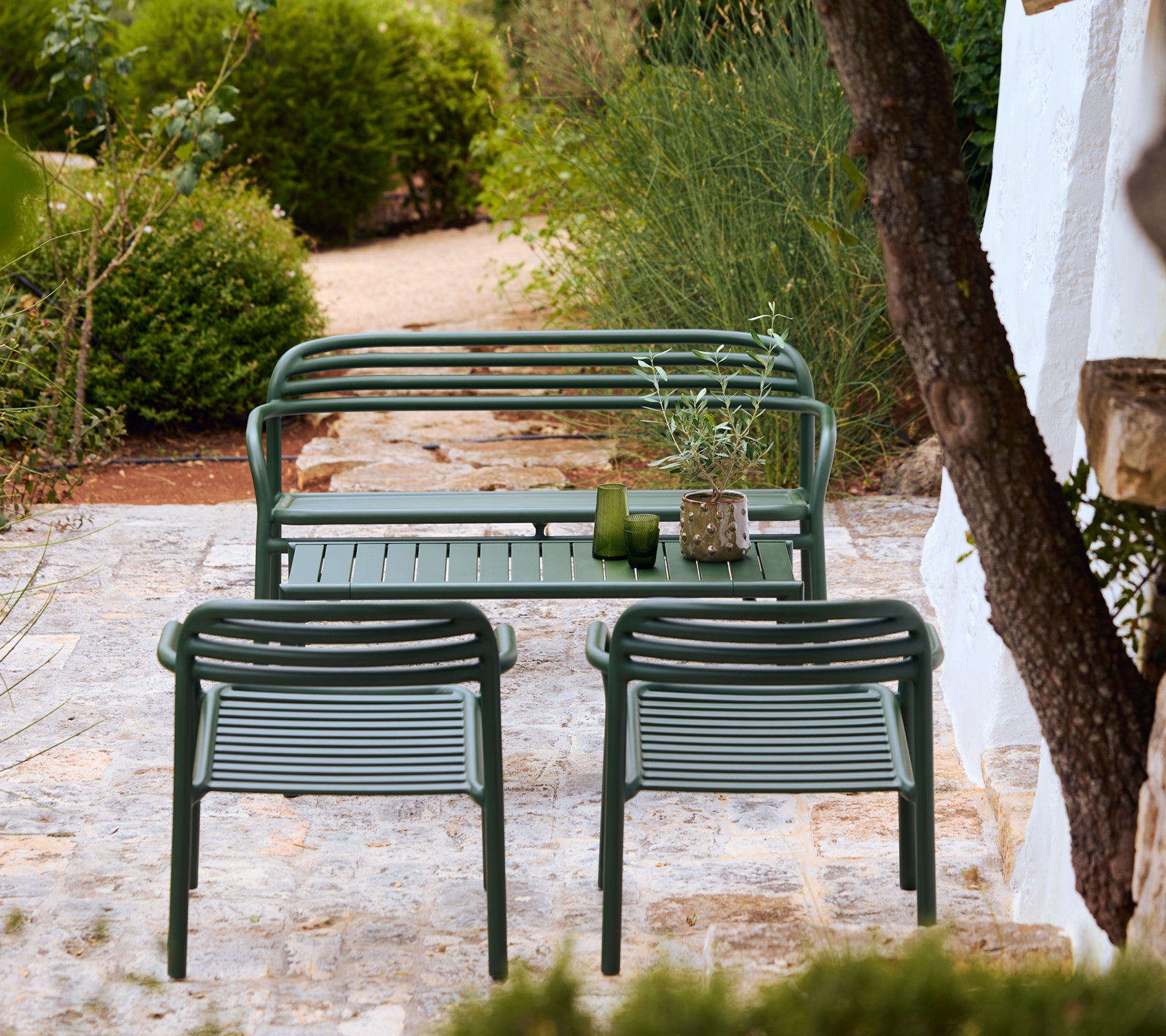 Moderne groene bank en stoelen in een stijlvolle buitenlounge-omgeving.