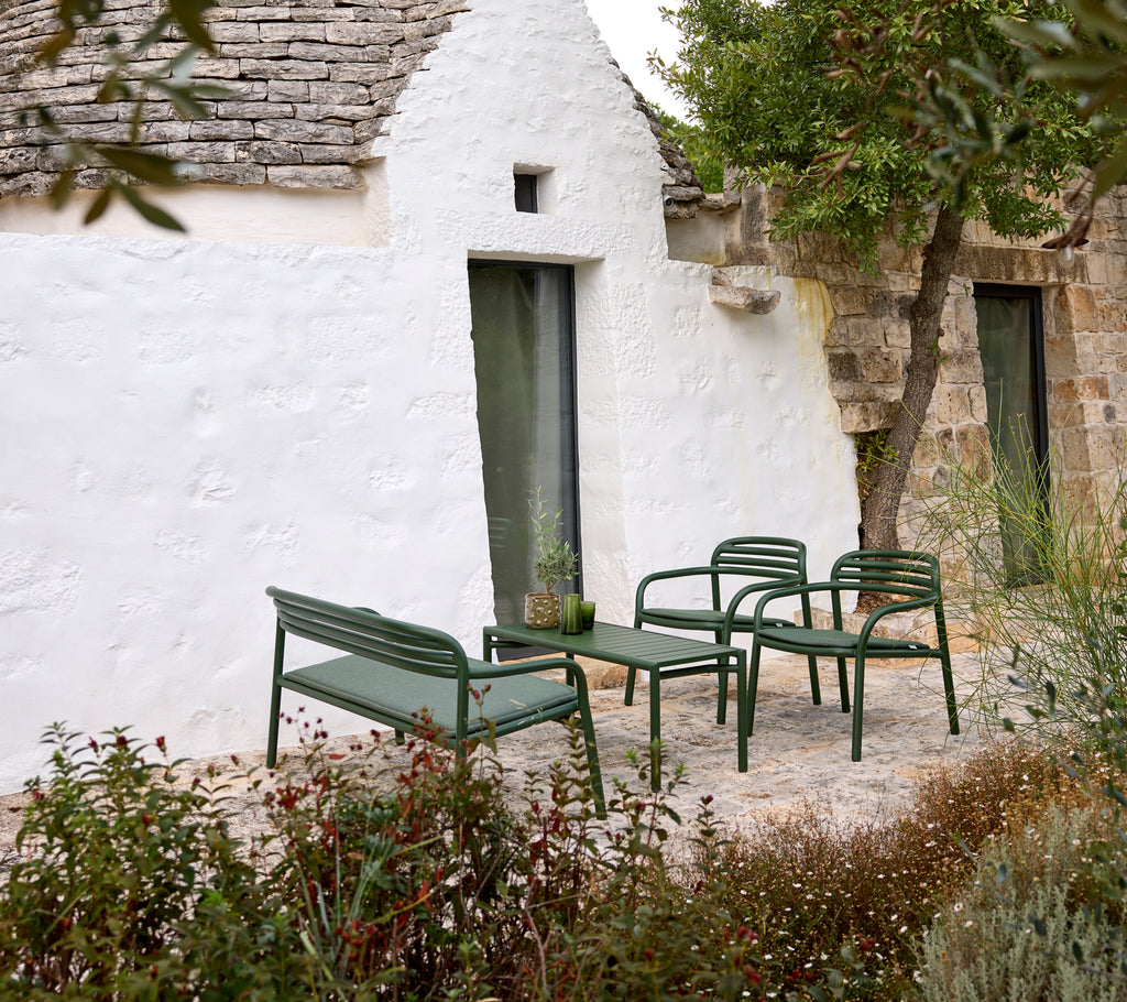 Groene tuinbank en stoelen met een salontafel in een gezellige setting.