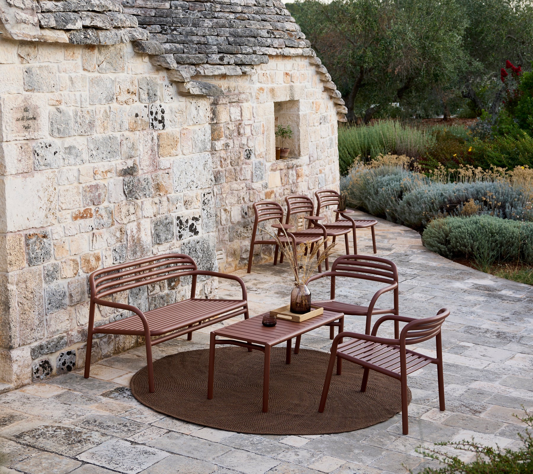 Bruine buitenbank, stoelen en tafelset in een modern loungegebied.