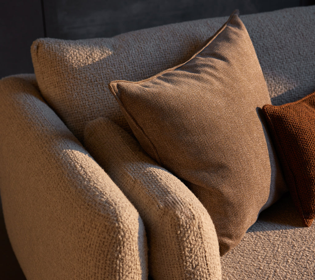 Gezellige hoeksalon met textuurstof en Essence-kussens in warme tinten die comfort en stijl aan de ruimte toevoegen.