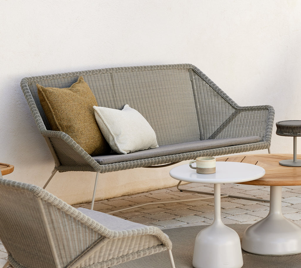 Moderne loungegebied met een grijze bank met kussens en ronde tafels.