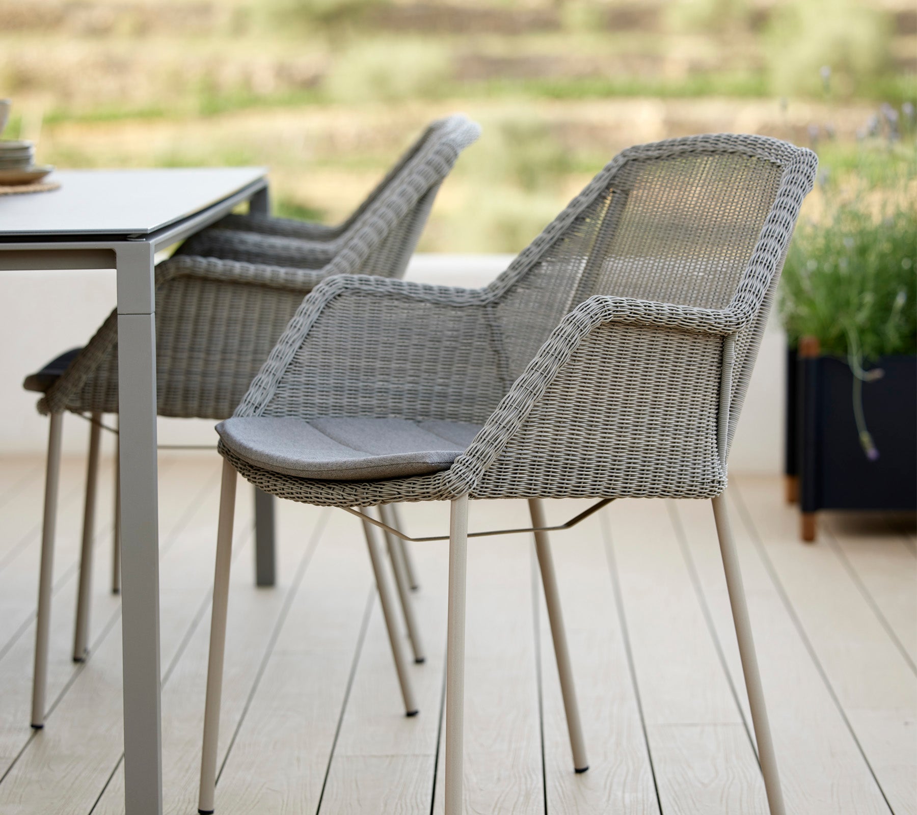 Twee stijlvolle geweven stoelen naast een moderne tafel, met een elegante vormgeving en comfortabele kussens, ideaal om te ontspannen in een serene omgeving.
