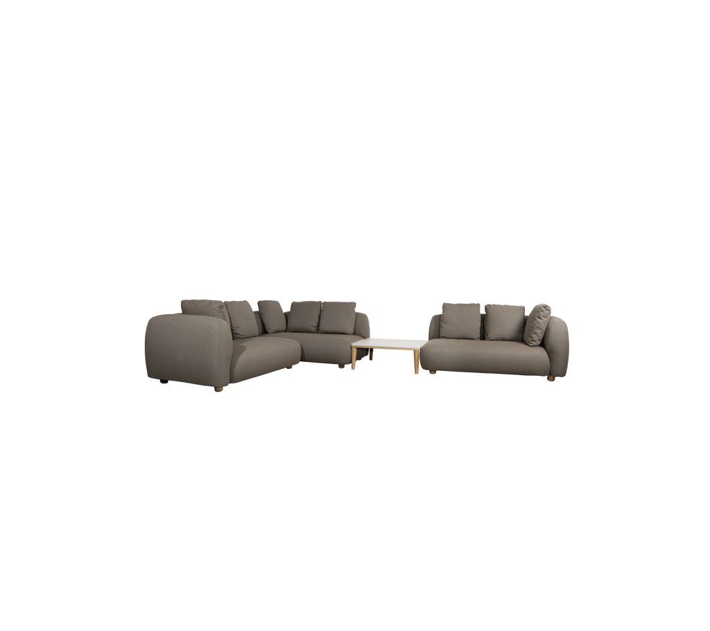 Moderne taupe bank met kussens en een lichte tafel in een lounge-instelling.