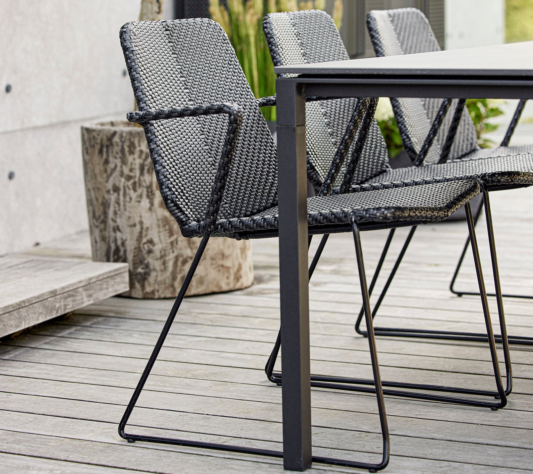 Een set moderne zwarte gevlochten stoelen rond een strak tafel, die eigentijds ontwerp en vakmanschap toont.