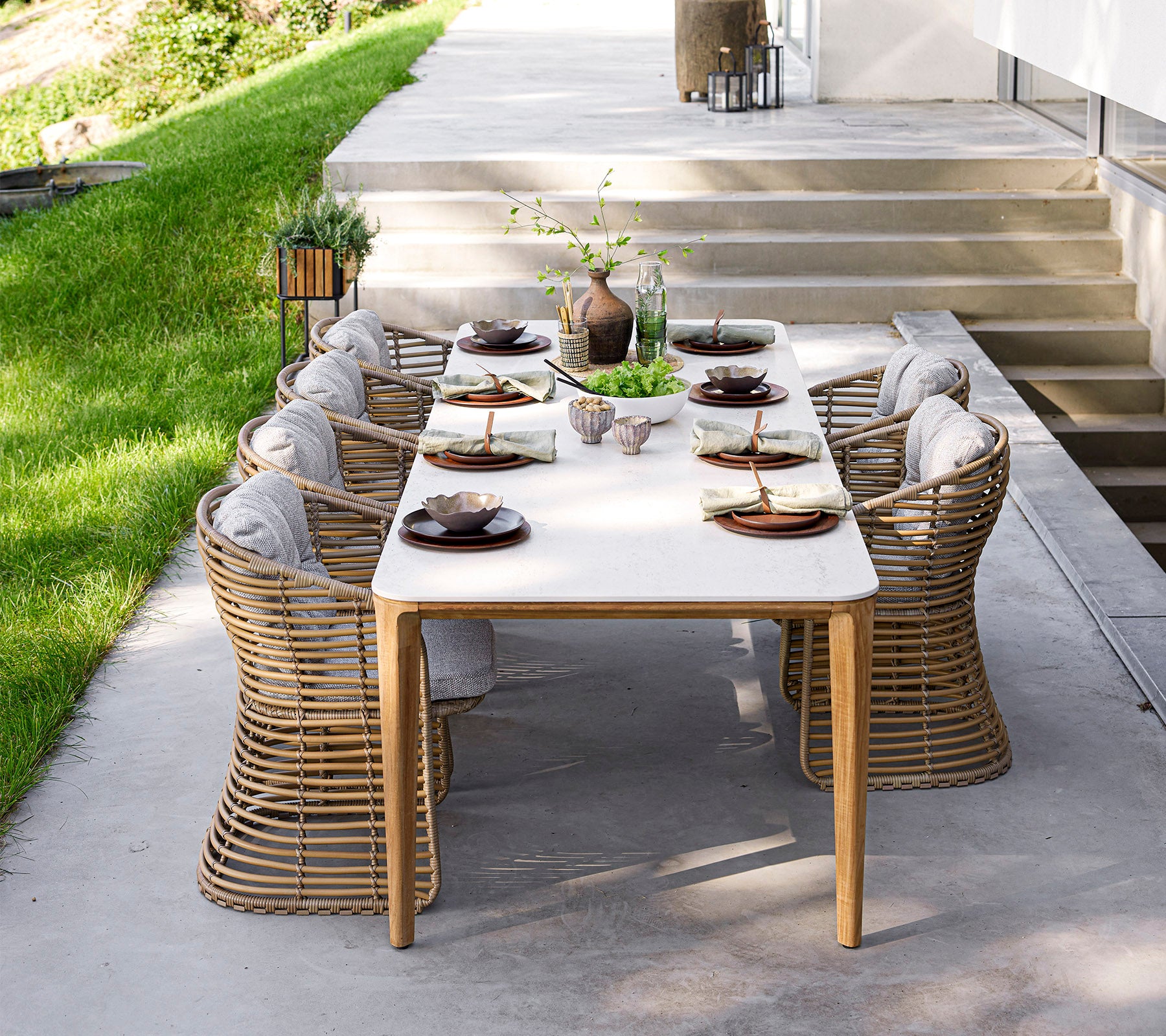Een stijlvol eettafel met elegant servies en comfortabele stoelen, omgeven door groen en natuurlijk licht. Perfect voor bijeenkomsten.