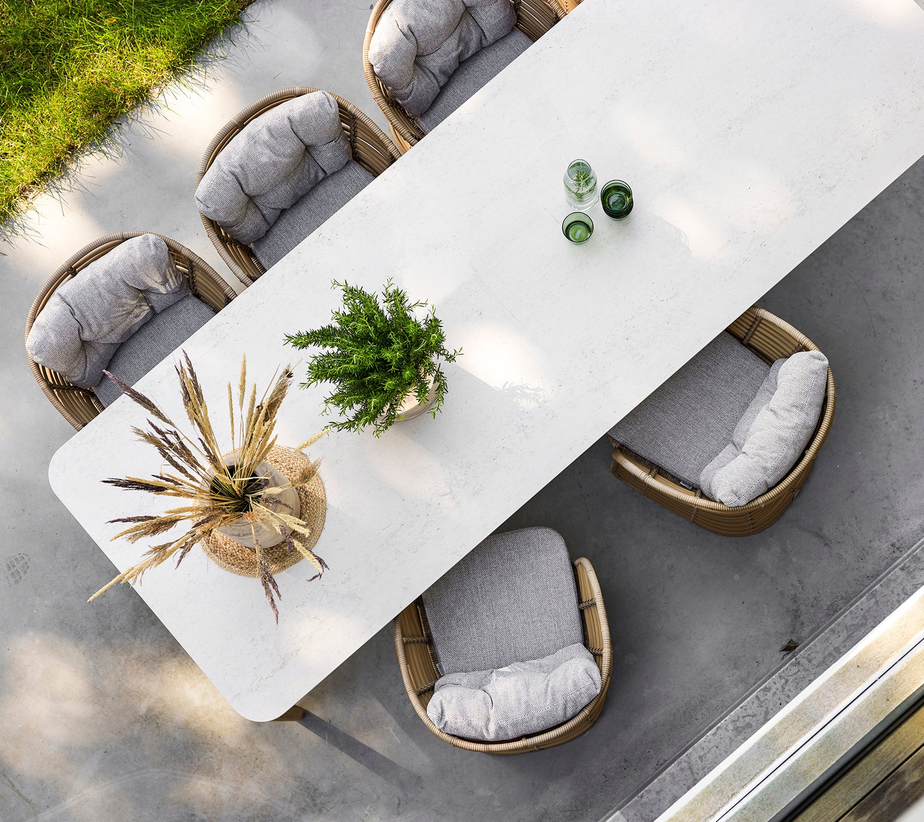 Een stijlvolle rechthoekige tafel omringd door vier comfortabele stoelen, versierd met groen en decoratieve elementen bovenop.