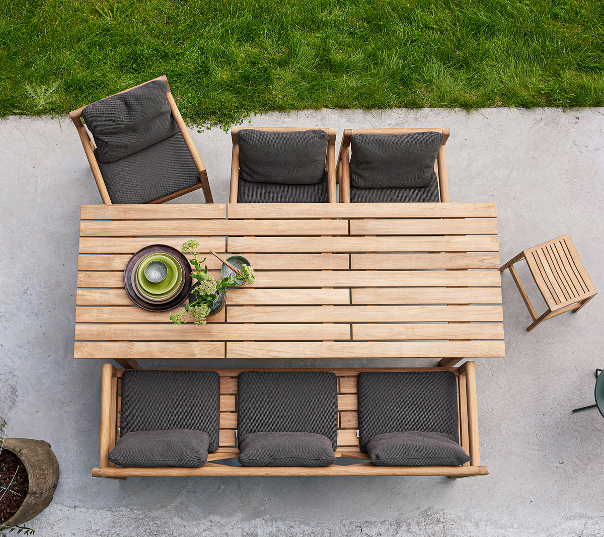 Een houten eettafel met vier gewatteerde stoelen en een schaal met groen, opgesteld voor een uitnodigende bijeenkomst.