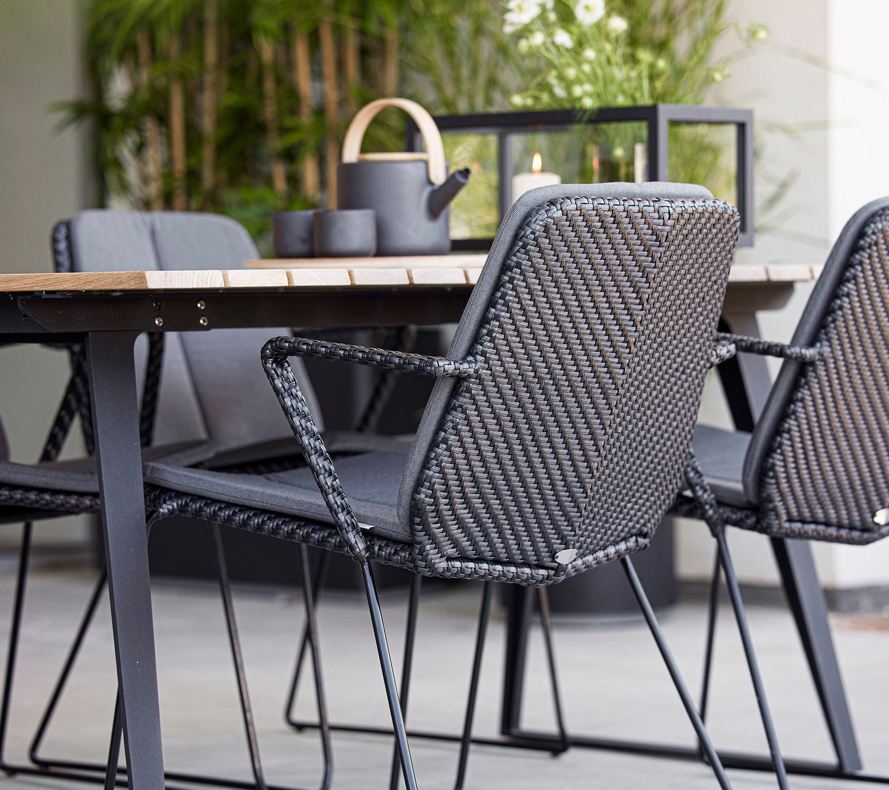 Contemporane zitplaatsen met grijze gevlochten stoelen rond een houten tafel, aangevuld met decoratieve items in een stijlvolle opstelling.