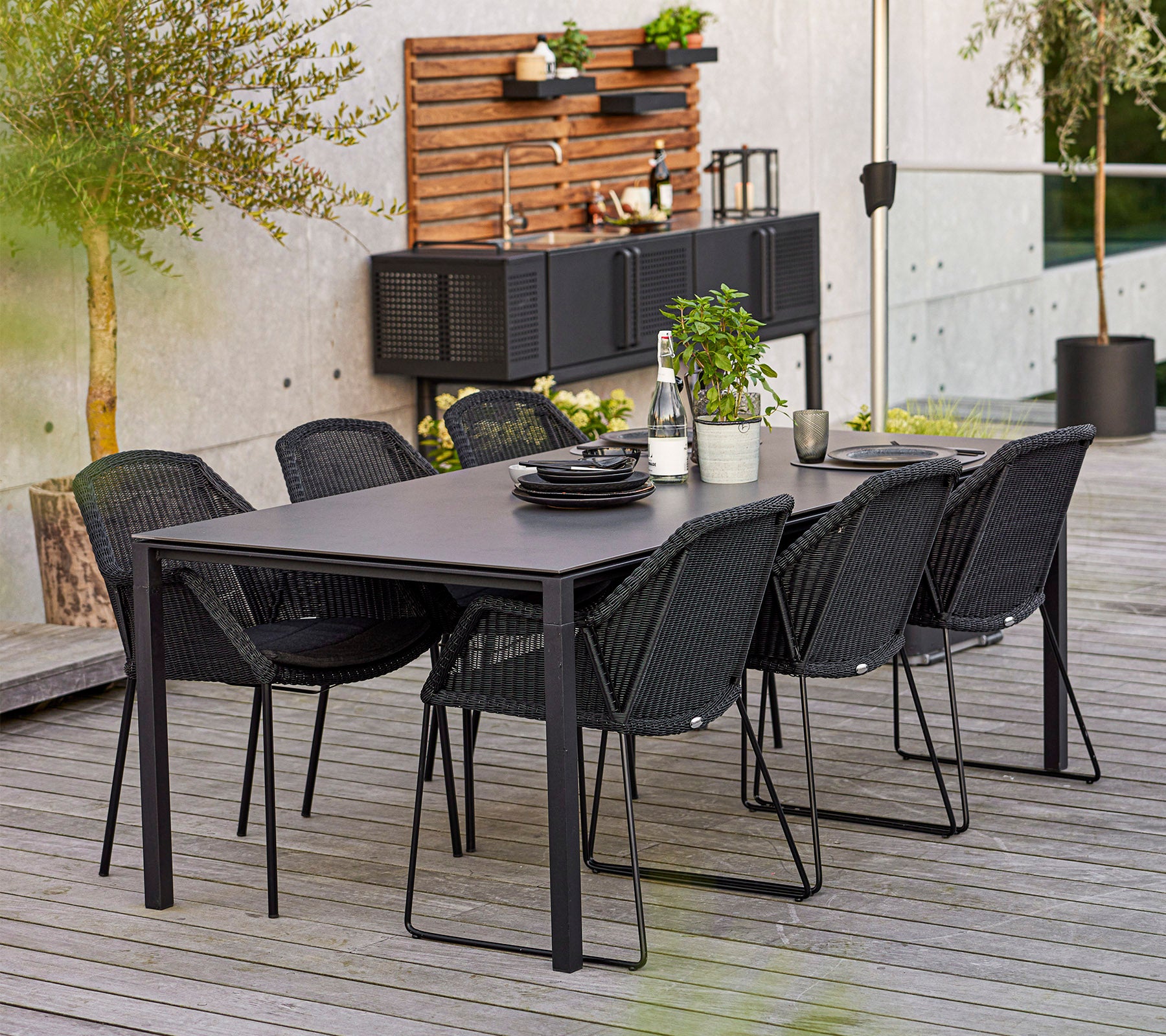 Een modern eettafelset met een rechthoekige tafel en zes stijlvolle stoelen, aangevuld met decoratieve planten en servies.