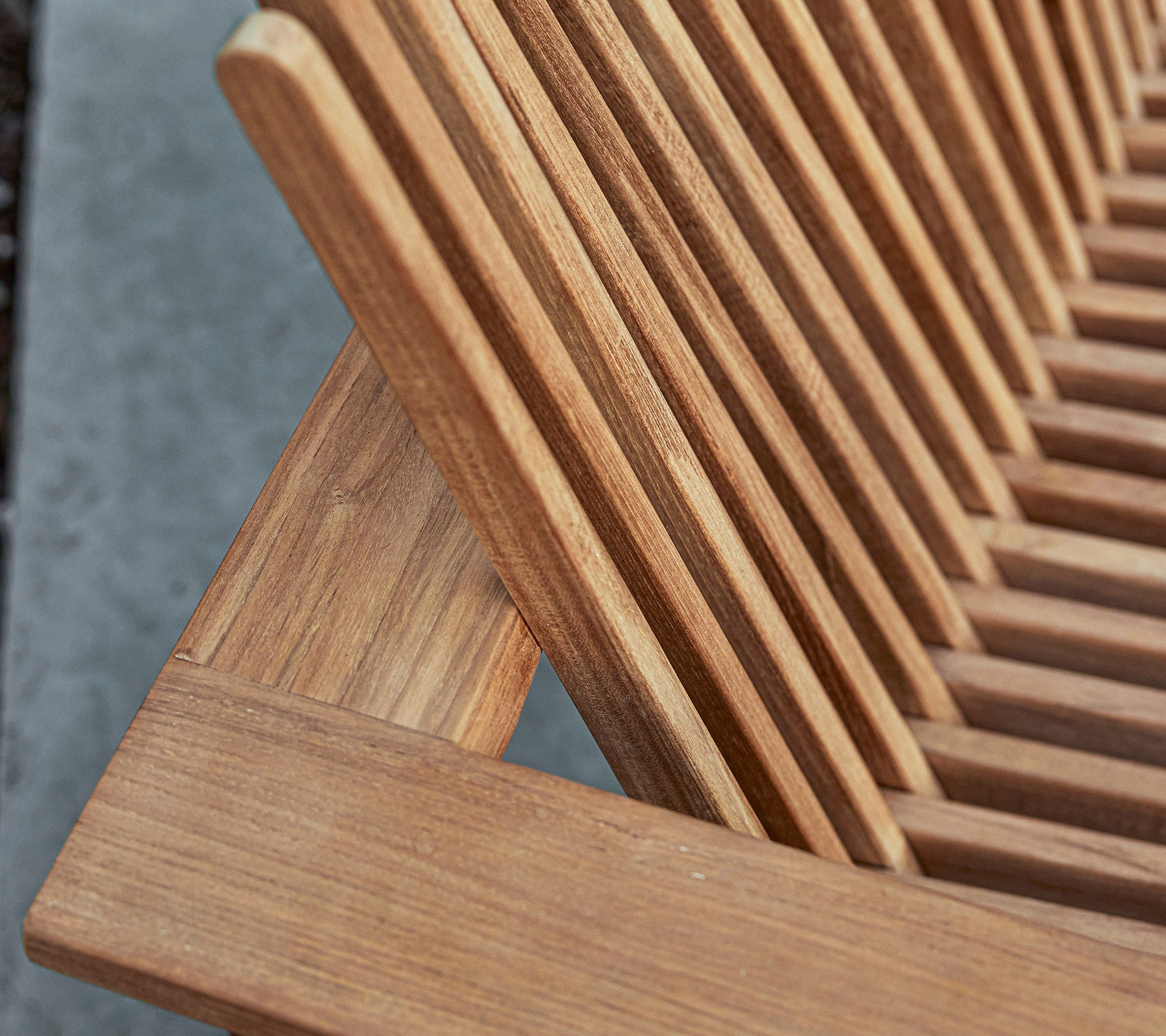 Close-up van een houten meubelstuk met lattenontwerp, dat de natuurlijke nerf en ambachtsdetails laat zien.