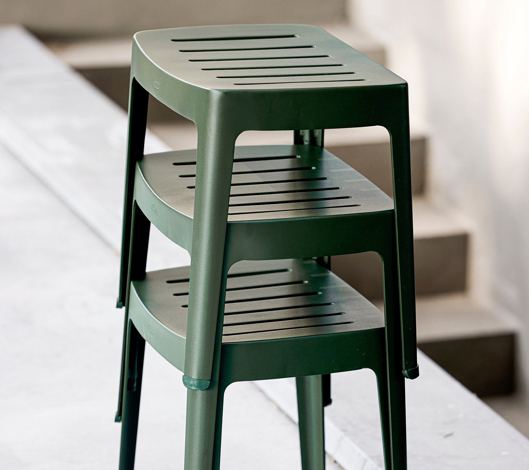 Gestapelde groene kunststofkrukken met geslepen zittingen, ontworpen voor casual gebruik. Ideaal voor veelzijdige zitarrangementen.