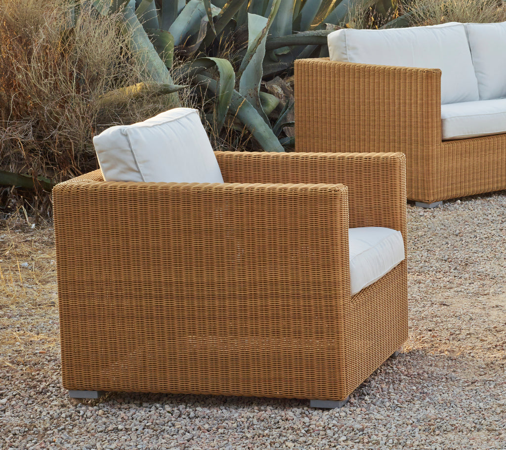 Bruine fauteuil met witte kussen in een moderne lounge-instelling.