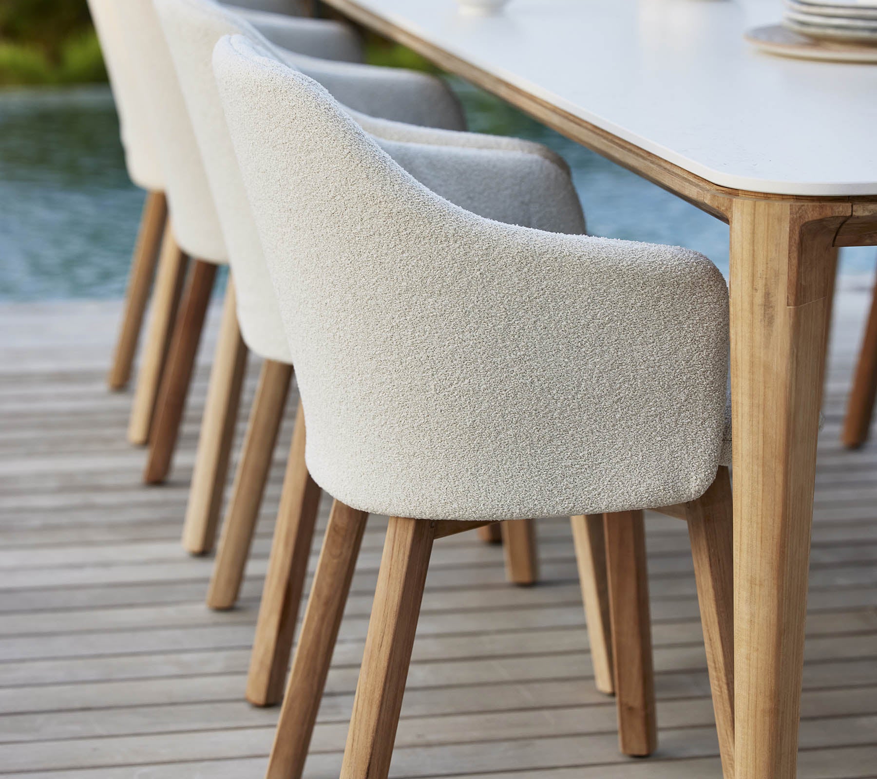 Stijlvolle gestoffeerde stoelen met houten poten staan naast een tafel en bieden een moderne en uitnodigende uitstraling voor diners of bijeenkomsten.