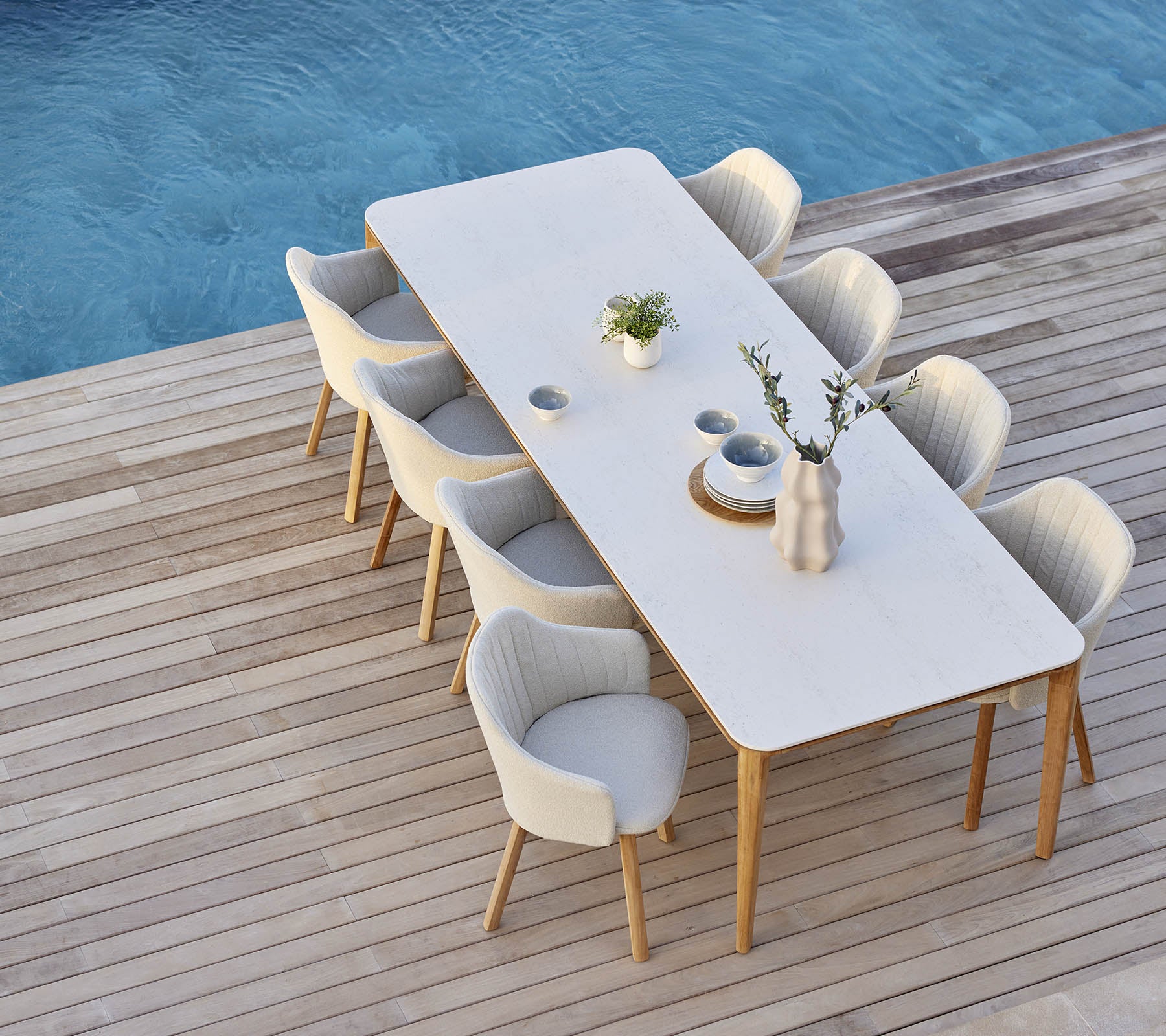 Elegante dinersetup met een lange tafel omringd door comfortabele stoelen, versierd met een vaas en plantaccenten.