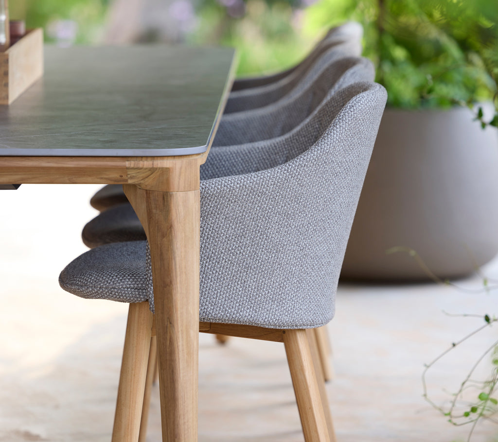 Moderne grijze stoel en tafel in een serene buitenomgeving.