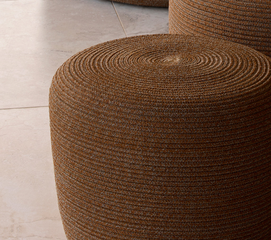 Kleine umbrabruine cirkelvormige poef met een gestructureerd geweven oppervlak, dat een stijlvolle accent biedt voor zitplaatsen of decoratie.