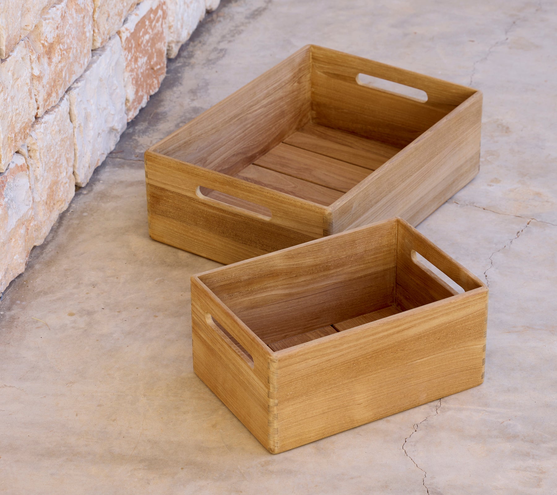 Twee houten kisten van verschillende groottes geplaatst op een betonnen oppervlak.