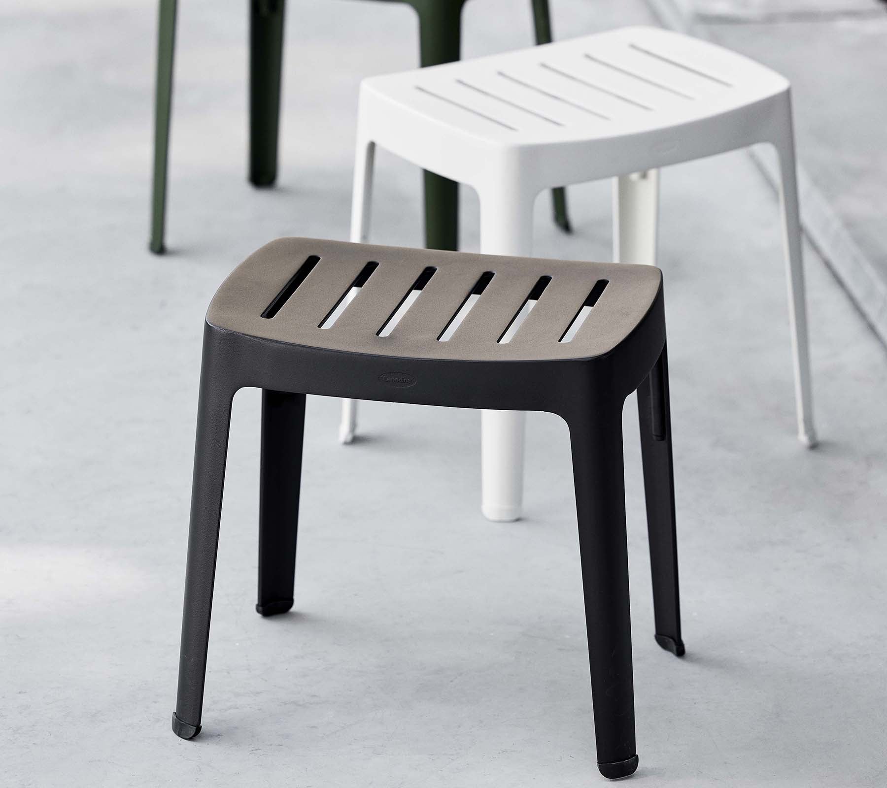 Stijlvolle kruk in zwart met een gelamineerd bovenblad, met een modern design; aangevuld met een witte kruk op de achtergrond.