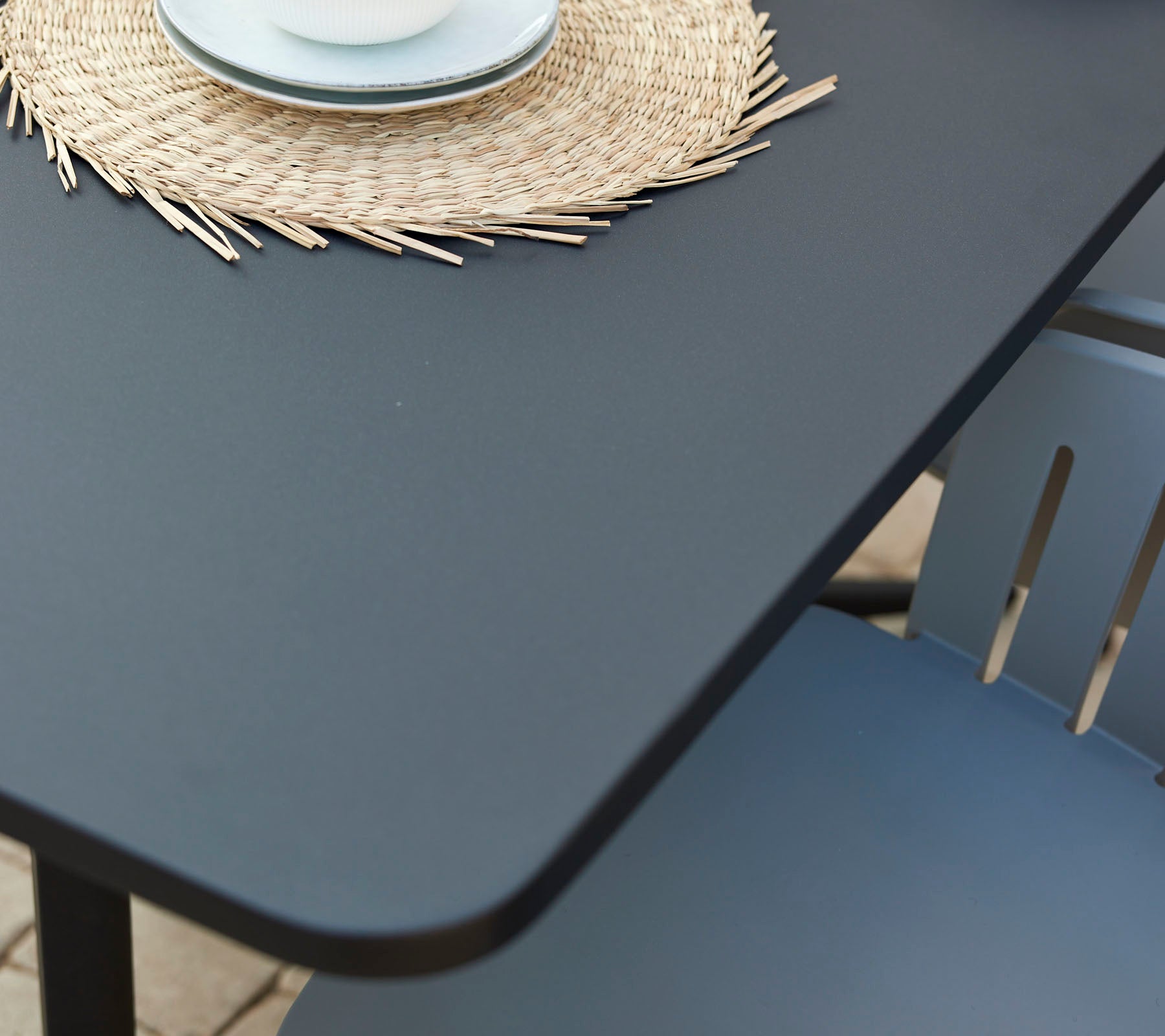 Een moderne café-tafel met een gladde oppervlakte, vergezeld van een decoratief rond placemat en een kop op een gezellige stoel.