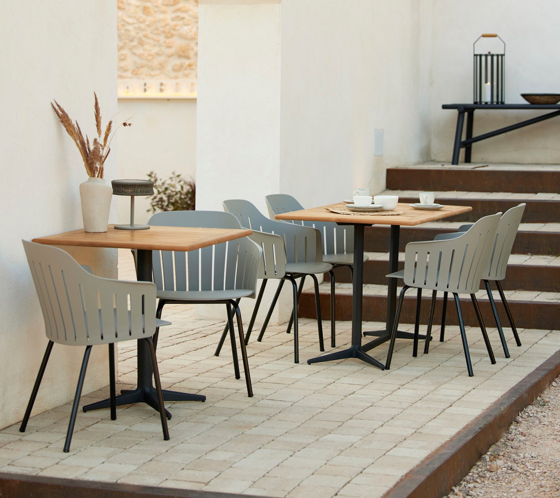 Een stijlvol café-inrichting met houten tafels, grijze stoelen en decoratieve accenten, ideaal voor informele bijeenkomsten en ontspanning.
