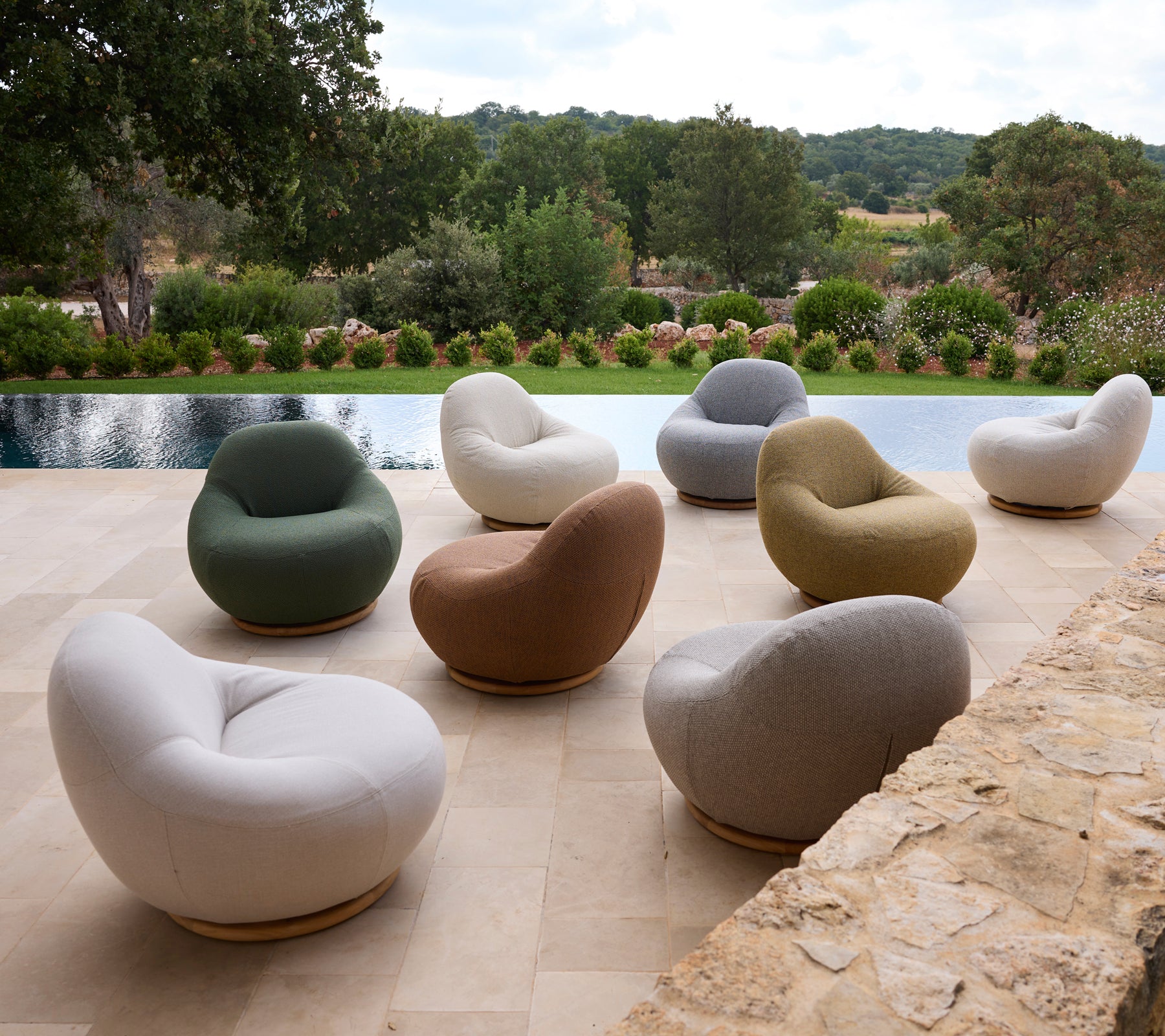 Set van moderne stoelen in verschillende kleuren rond een zwembad geplaatst.