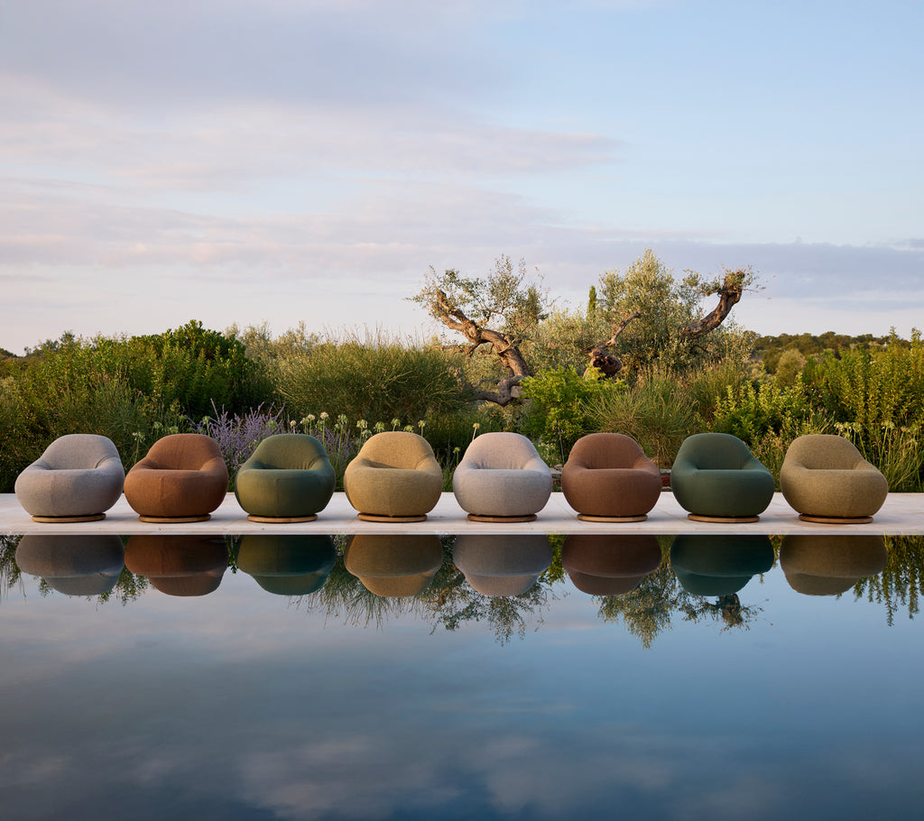 Moderne tuinmeubelen in verschillende kleuren rond het zwembad gerangschikt.