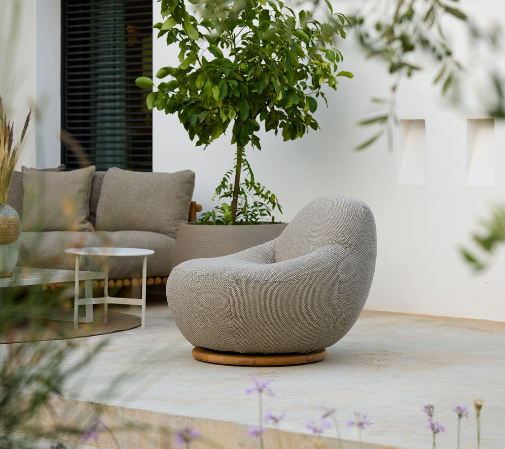 Moderne lounge-instelling met een grijze stoel, grijze kussen en witte tafel.