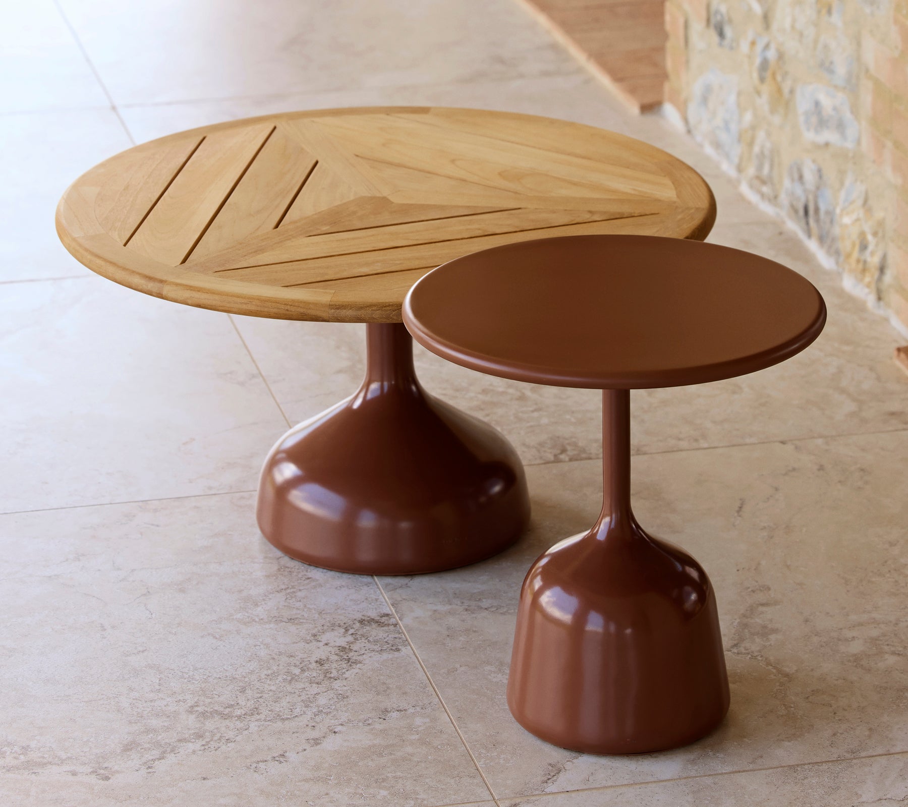 Twee salontafels, één met een houten blad en geometrisch design, de andere met een gladde, woestijnrode afwerking, die een moderne esthetiek delen.