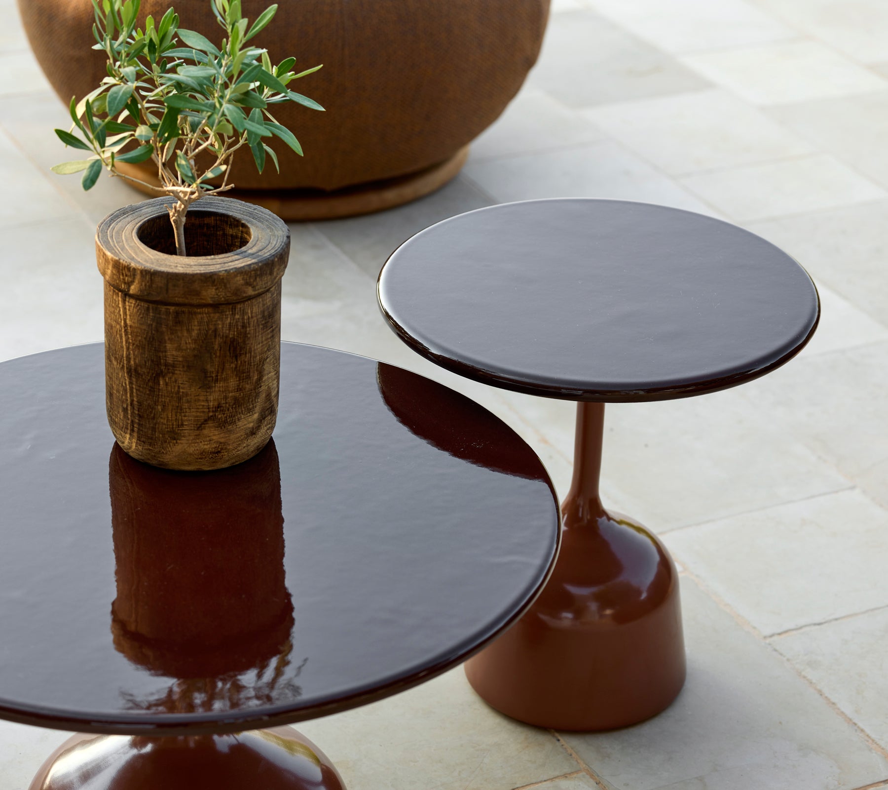 Twee moderne bruine tafels met een plantenpot in een stijlvolle lounge-instelling.