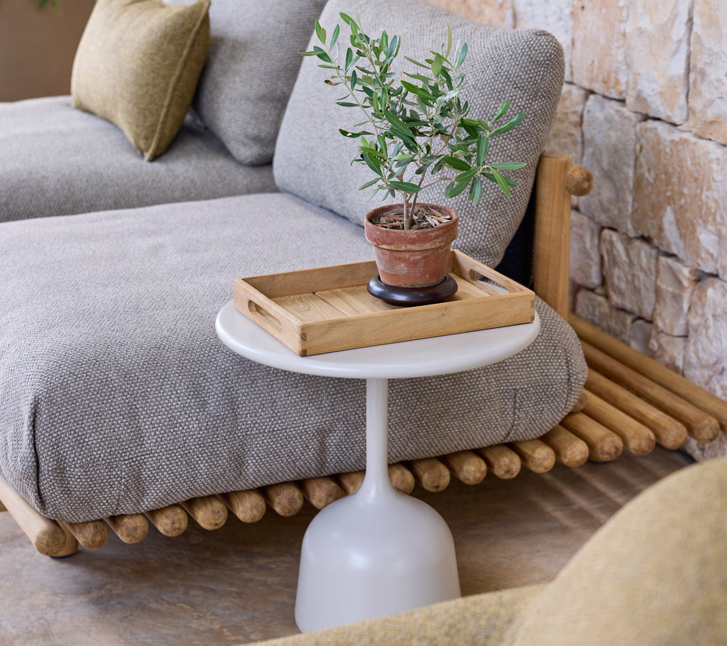 Moderne lounge-inrichting met een grijze bank, een witte bijzettafel en een groene plant.