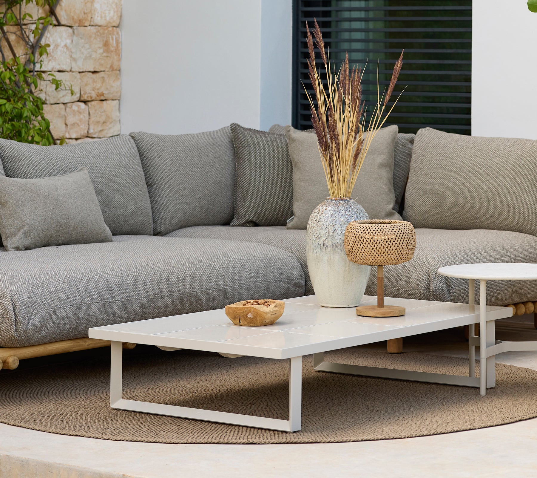 Moderne loungegebied met een grijze bank en een witte salontafel met decoratie.