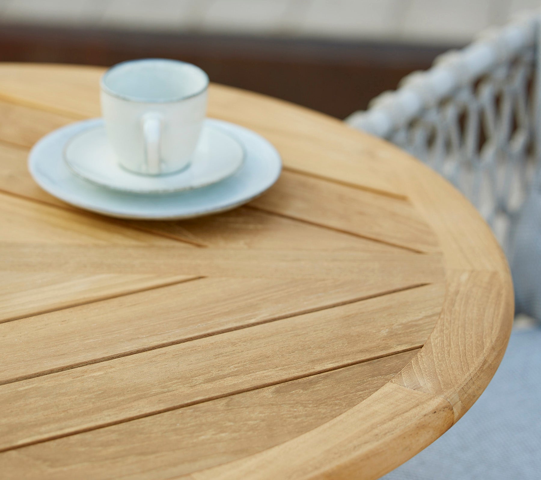 Een houten tafel met een koffiekop en schotel erop, die een minimalistische en uitnodigende cafésfeer laat zien.