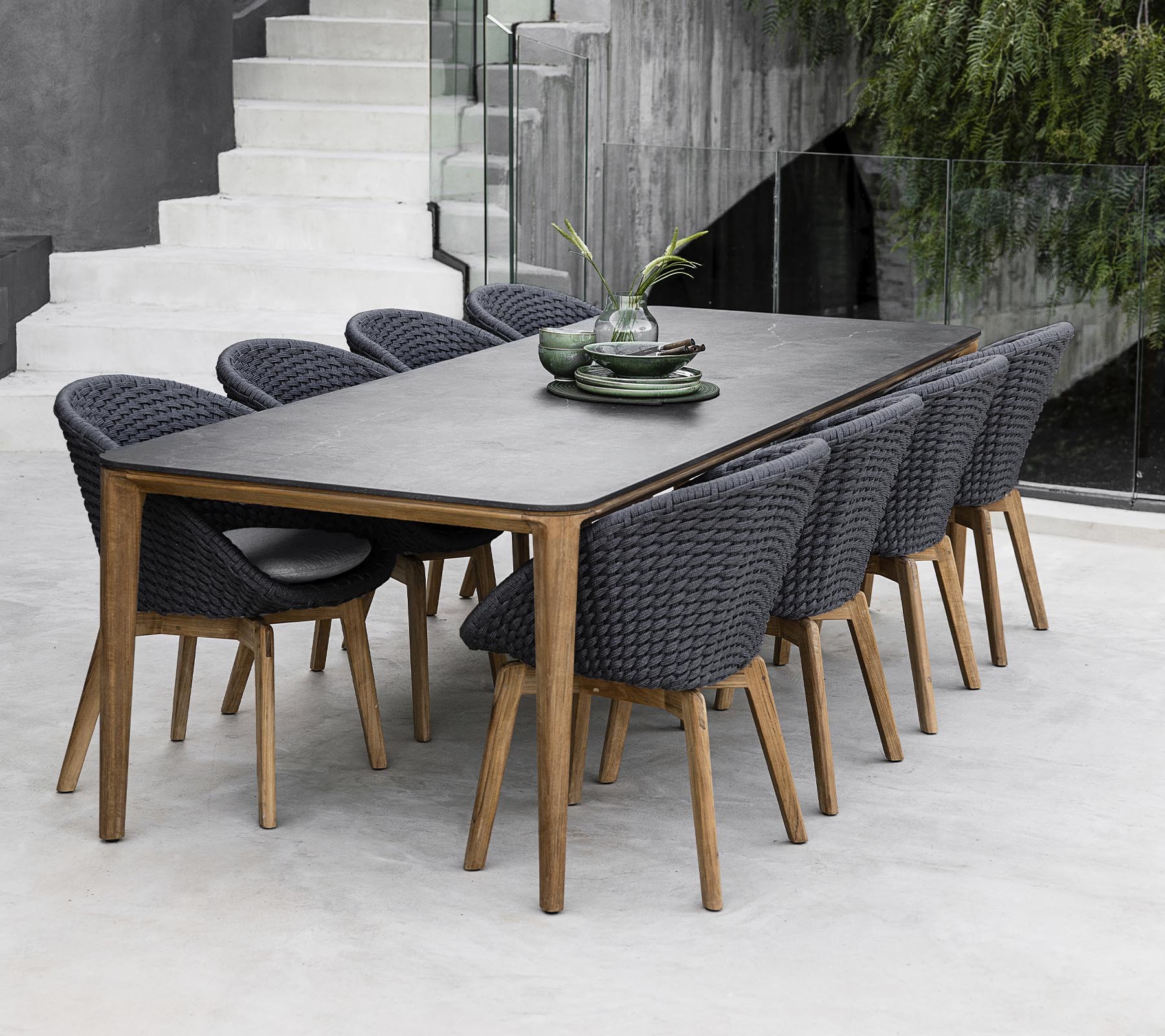 Een moderne tafel omringd door acht stijlvolle stoelen, versierd met decoratieve planten op de tafel in een strakke, minimalistische setting.