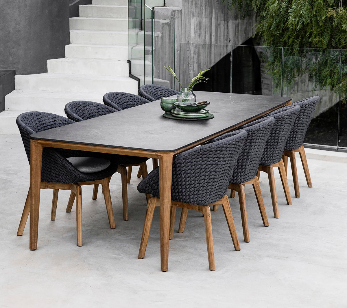 Een moderne tafel omringd door acht stijlvolle stoelen, versierd met decoratieve planten op de tafel in een strakke, minimalistische setting.