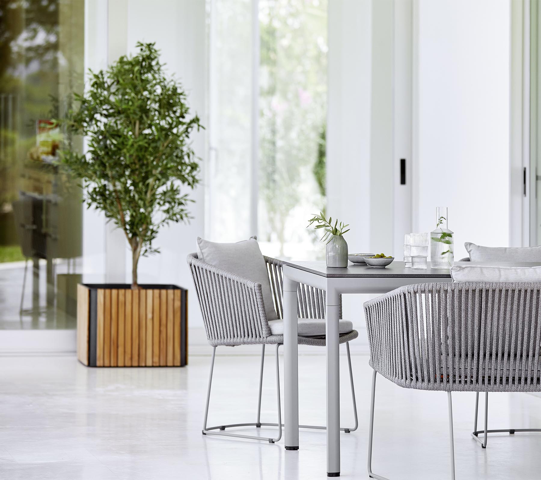Een moderne eetruimte met een elegant tafel, tekstuurstoelen en een decoratieve potplant die een stijlvolle en uitnodigende sfeer creëert.