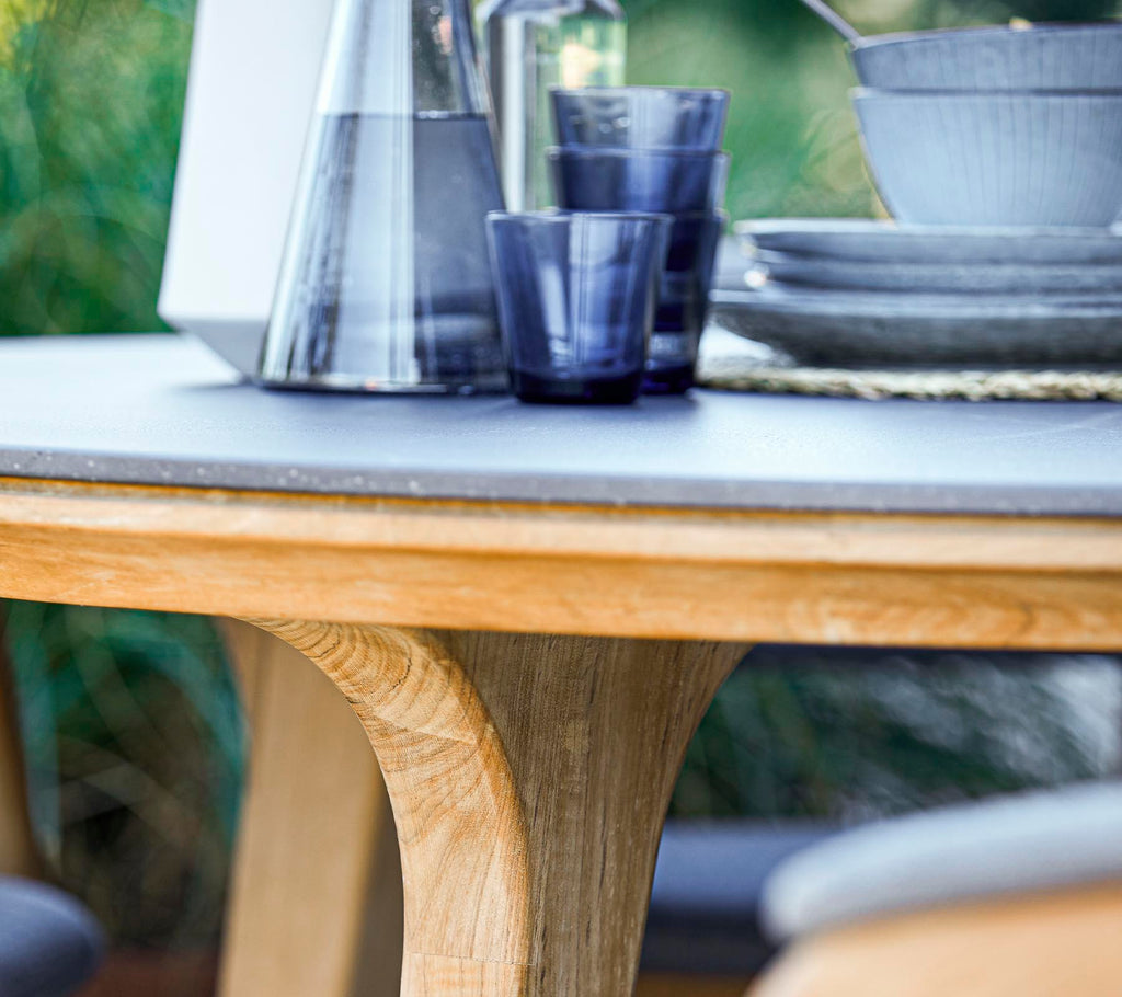 Een ronde houten tafel met een glad oppervlak, vergezeld van glazen en keramische schalen, die een stijlvolle eetopstelling creëert.