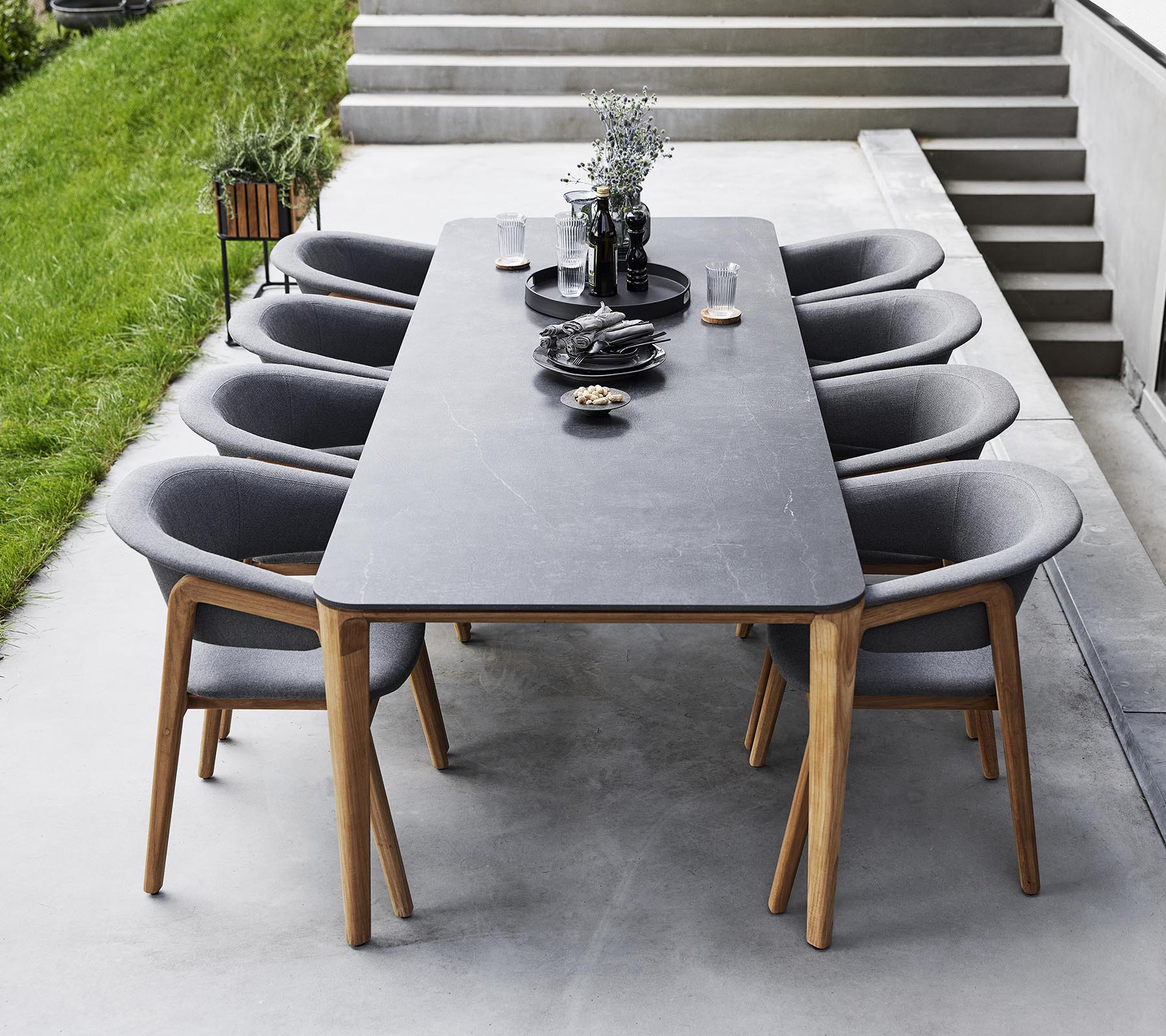 Stijlvolle dinersetup met een lange tafel omringd door moderne gestoffeerde stoelen, versierd met decoratieve items en groen.