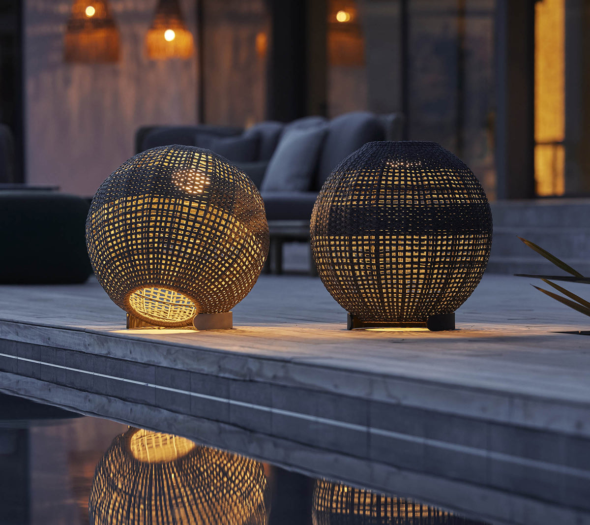 Twee ronde illusielampen met ingewikkelde patronen, die warm licht en reflecties op een oppervlak werpen, waardoor een gezellige sfeer ontstaat.