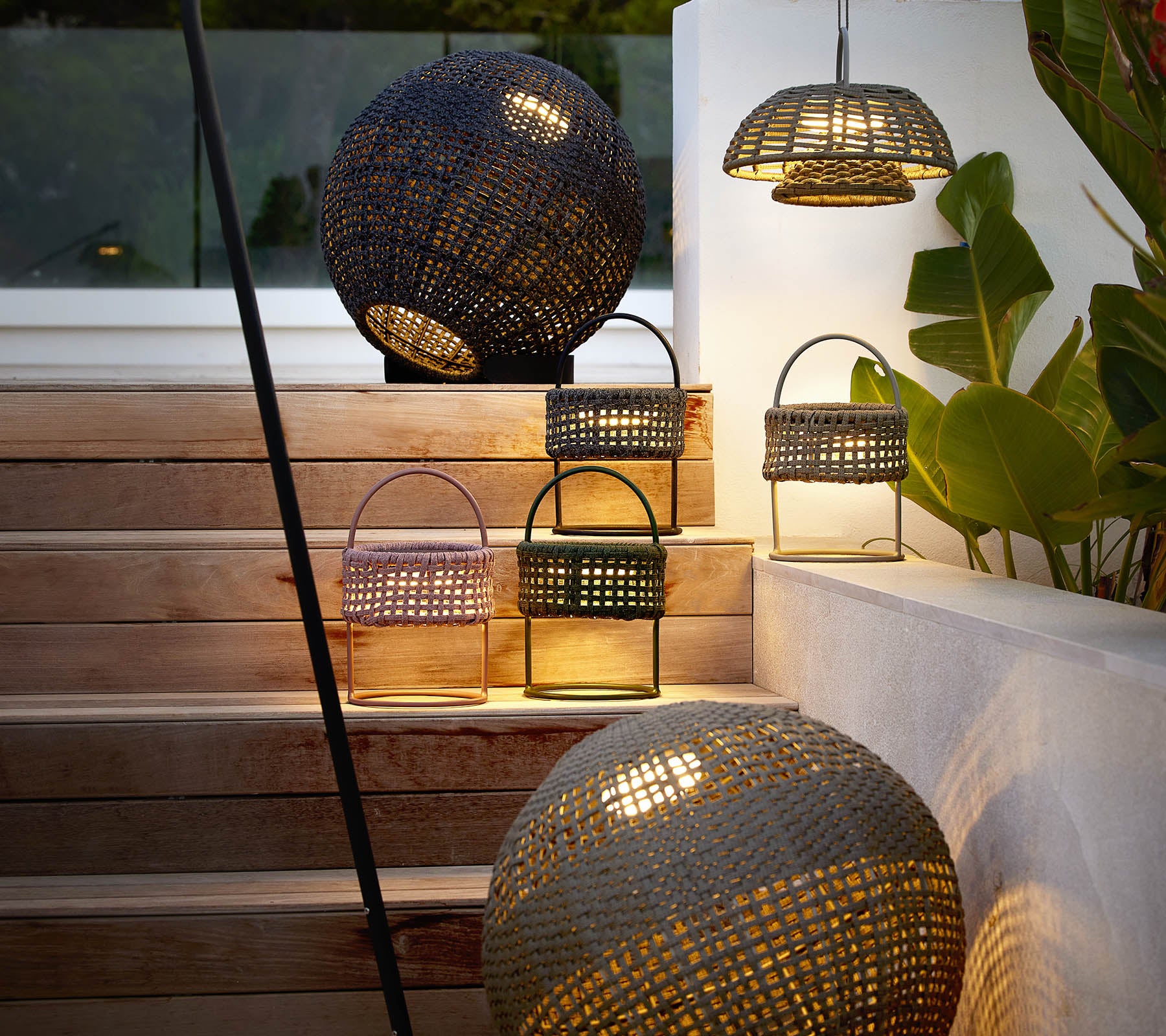 Een collectie stijlvolle illusielampen in verschillende vormen die een warme, uitnodigende gloed verspreiden temidden van decoratief groen.