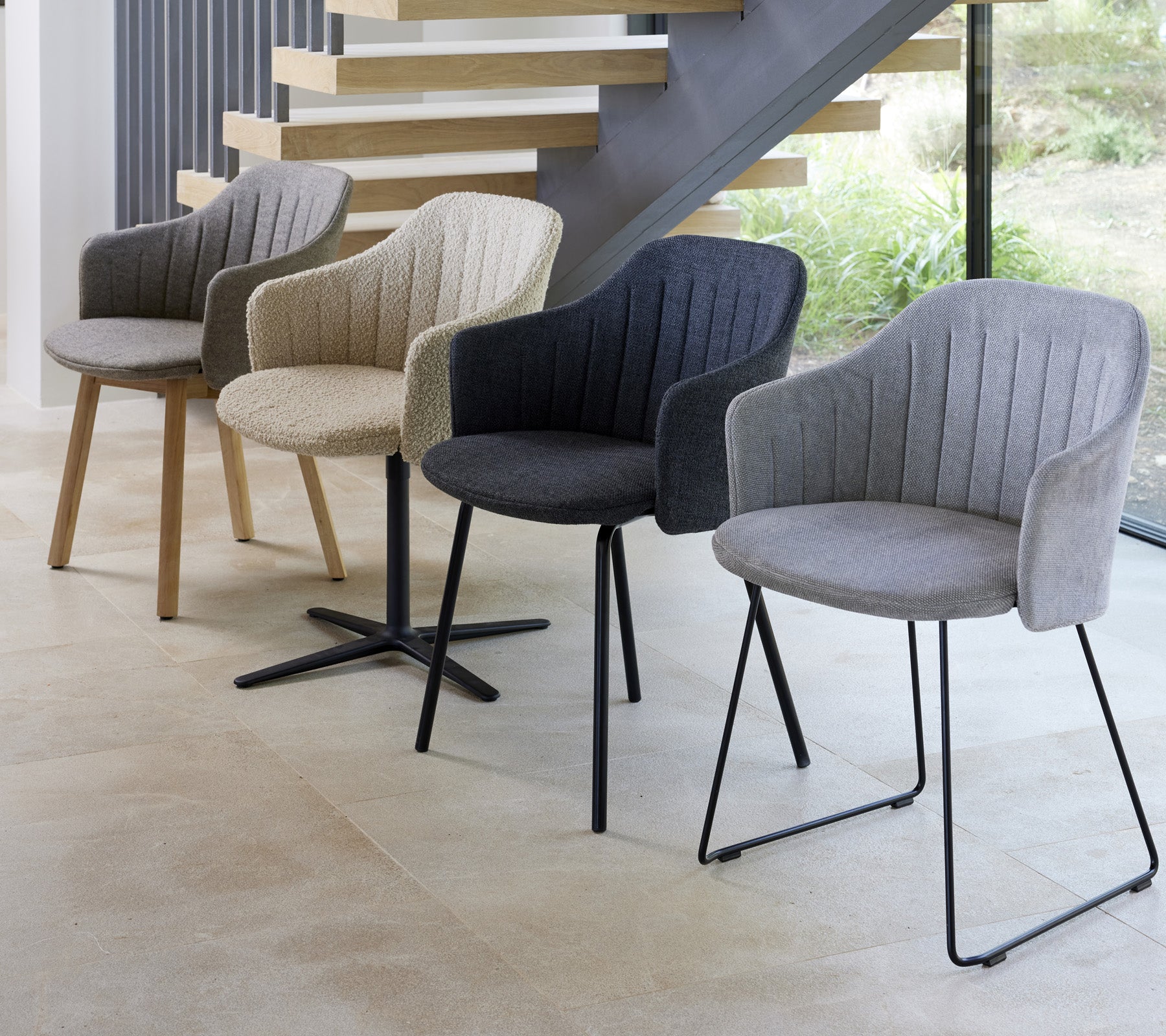 Vier moderne stoelen in verschillende kleuren en stijlen, tentoongesteld in een hedendaagse omgeving, die hun unieke ontwerpen laat zien.