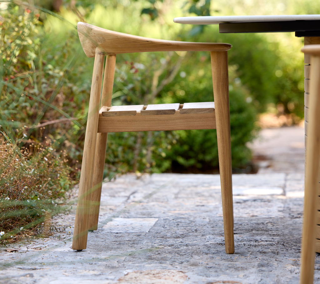 Moderne houten stoel naast een zwarte tafel in een buitenomgeving.