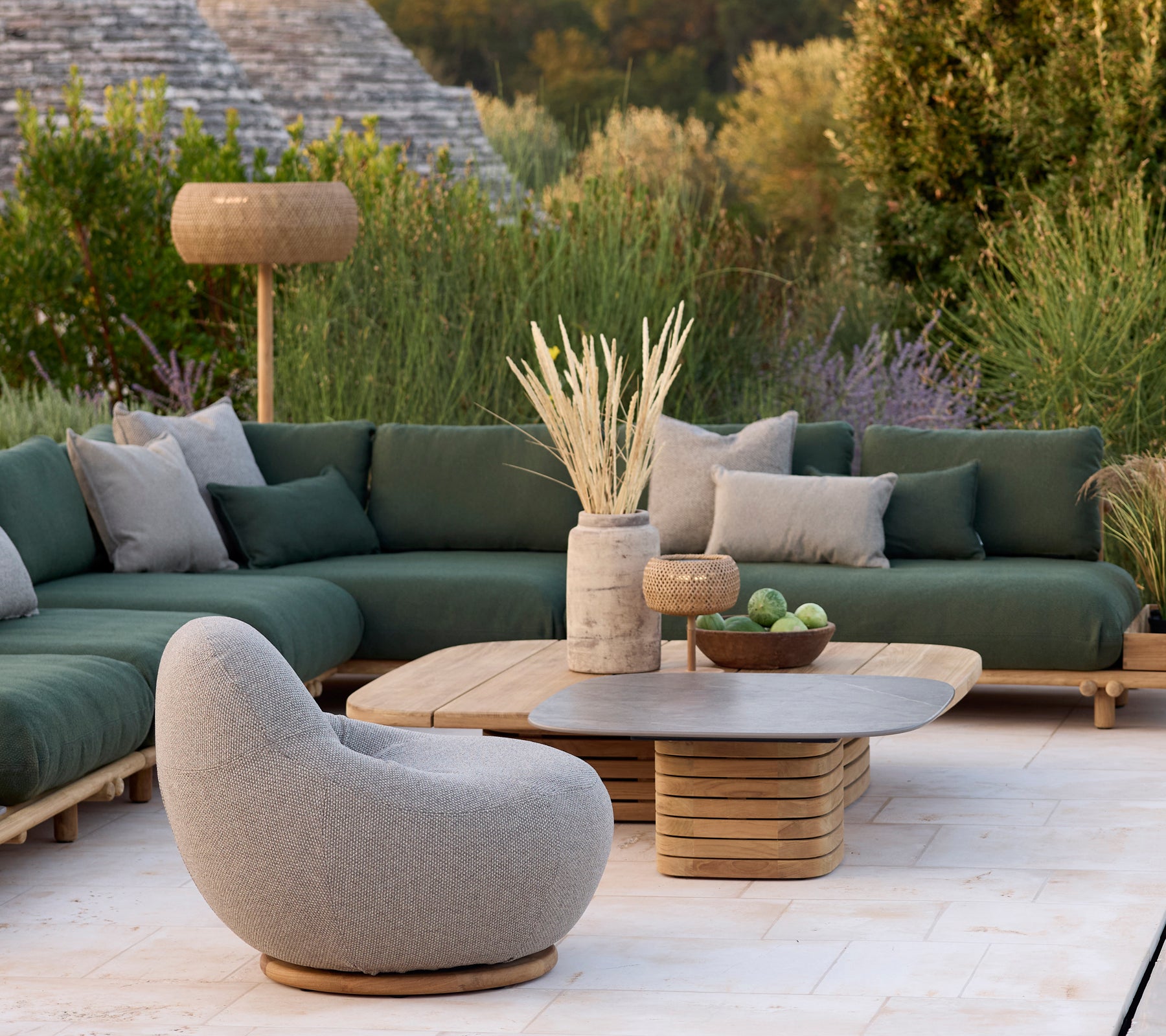 Moderne lounge-omgeving met een groene bank, grijze stoel en ronde salontafel.