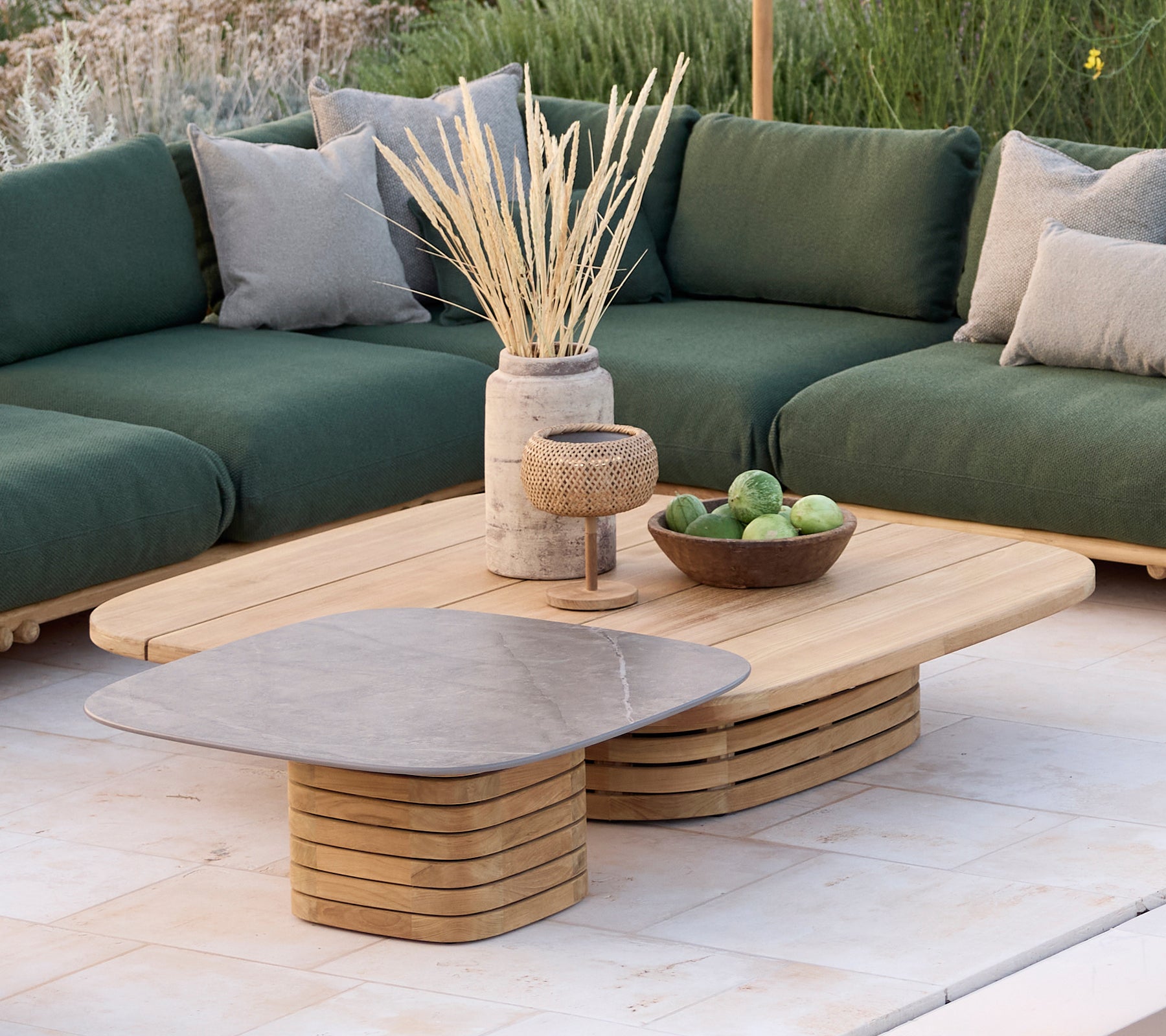 Moderne loungegebied met een groene bank met kussens, een houten salontafel en decoratieve items.