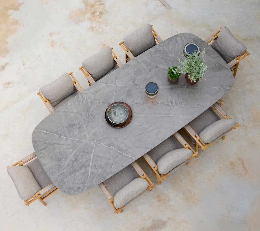 Moderne eetopstelling met een grijze tafel, beige kussens en houten stoelen.