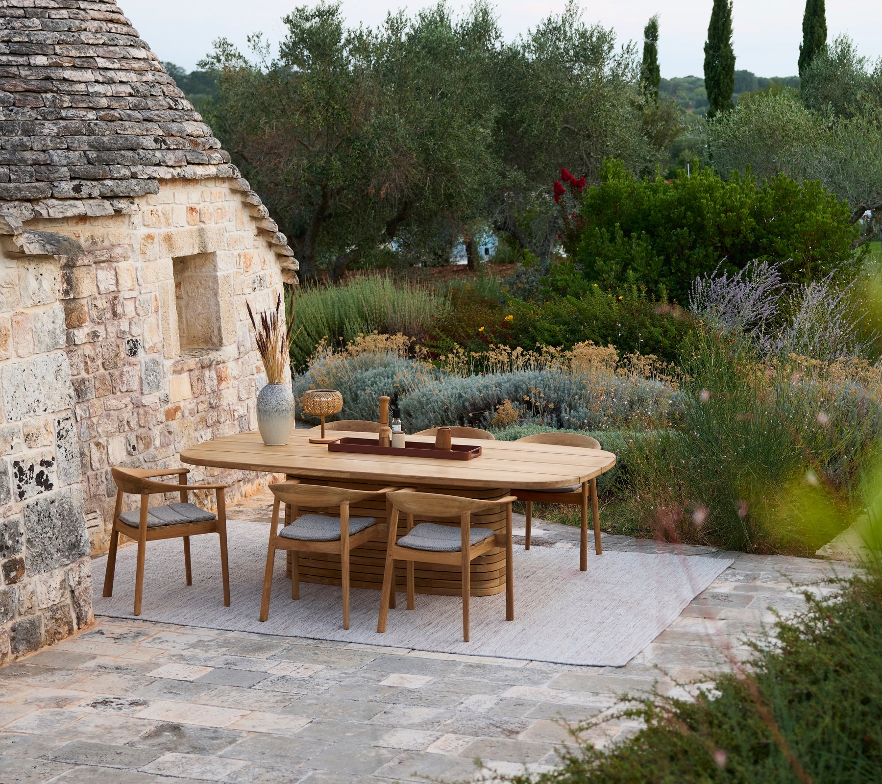 Moderne houten eettafel omringd door houten stoelen in een buiten tuinsetting.