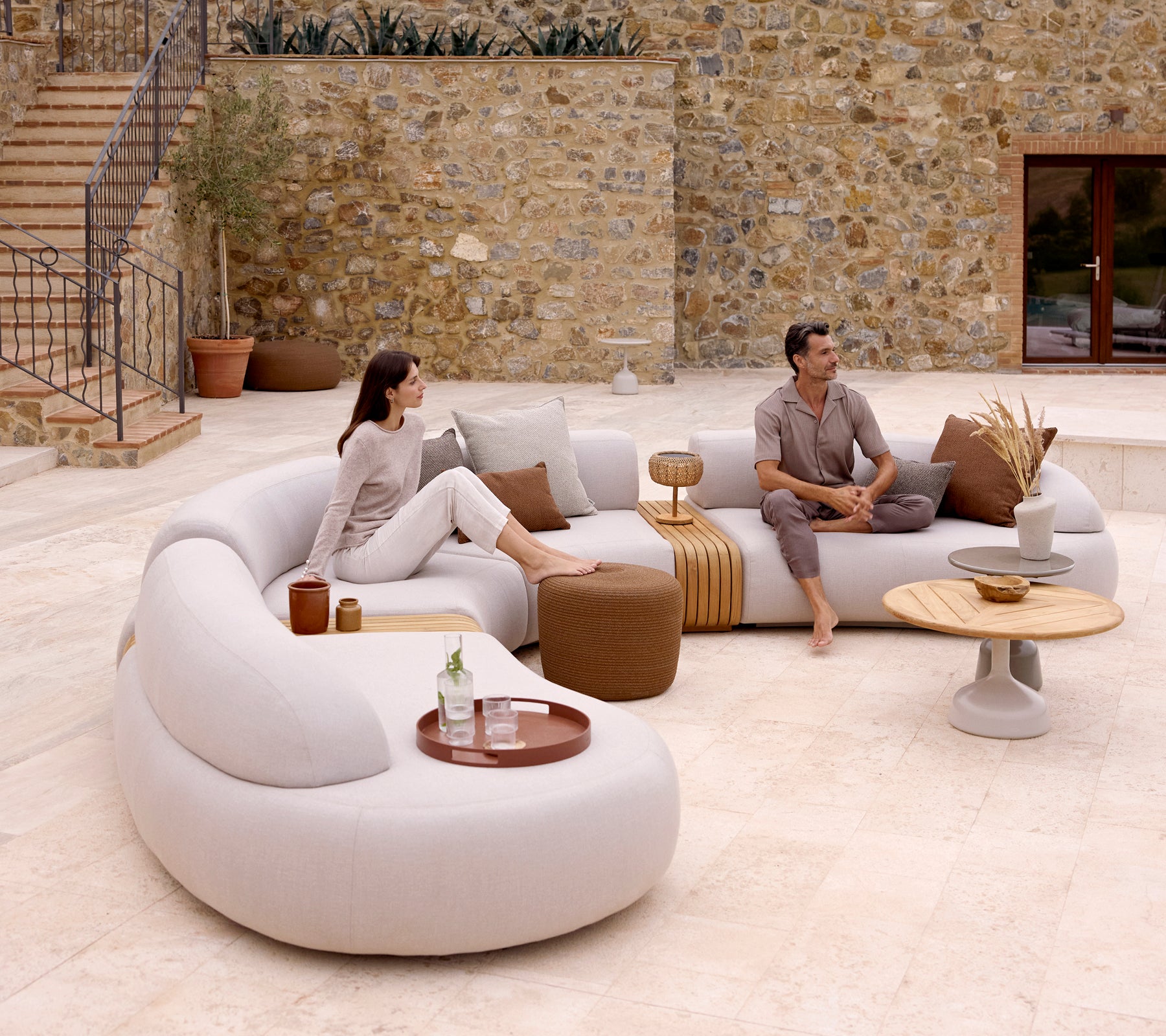 Een moderne lounge-instelling met een gebogen bank, een ronde voetenbank en een stijlvolle salontafel met een clubblad, wat een gezellige sfeer creëert.