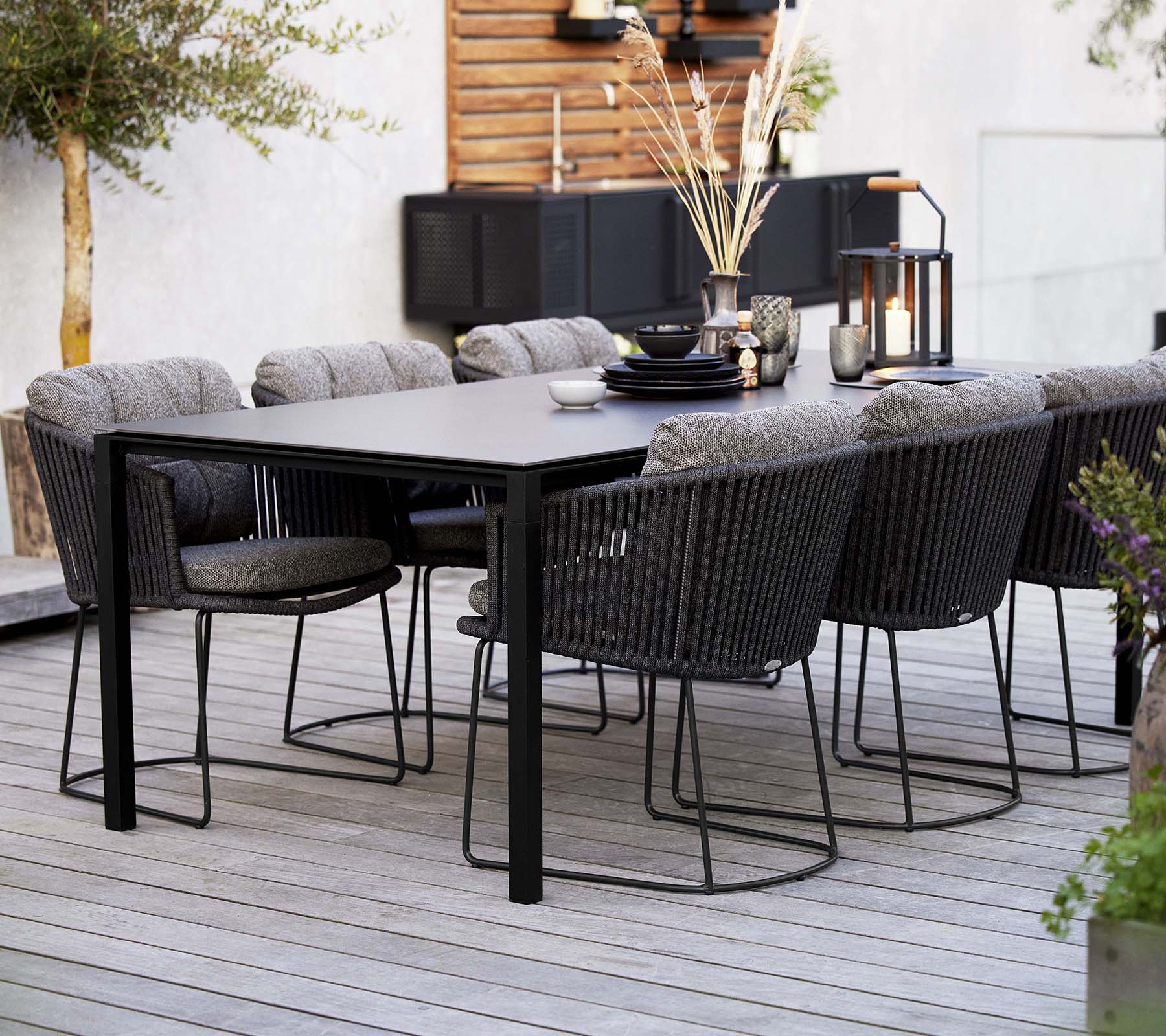 Een stijlvolle eetopstelling met een slank tafel omringd door comfortabele geweven stoelen, versierd met decoratieve elementen en planten.