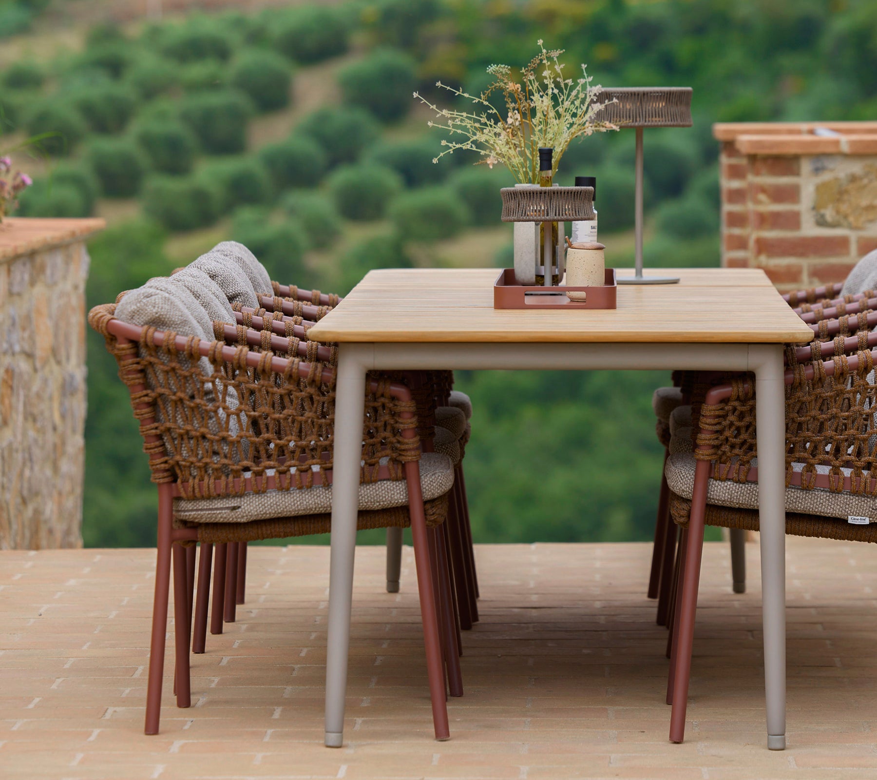Umberbruine eetstoelen rond een stijlvolle tafel, geaccentueerd met een clubtafel en decoratieve elementen, tegen een schilderachtige achtergrond.